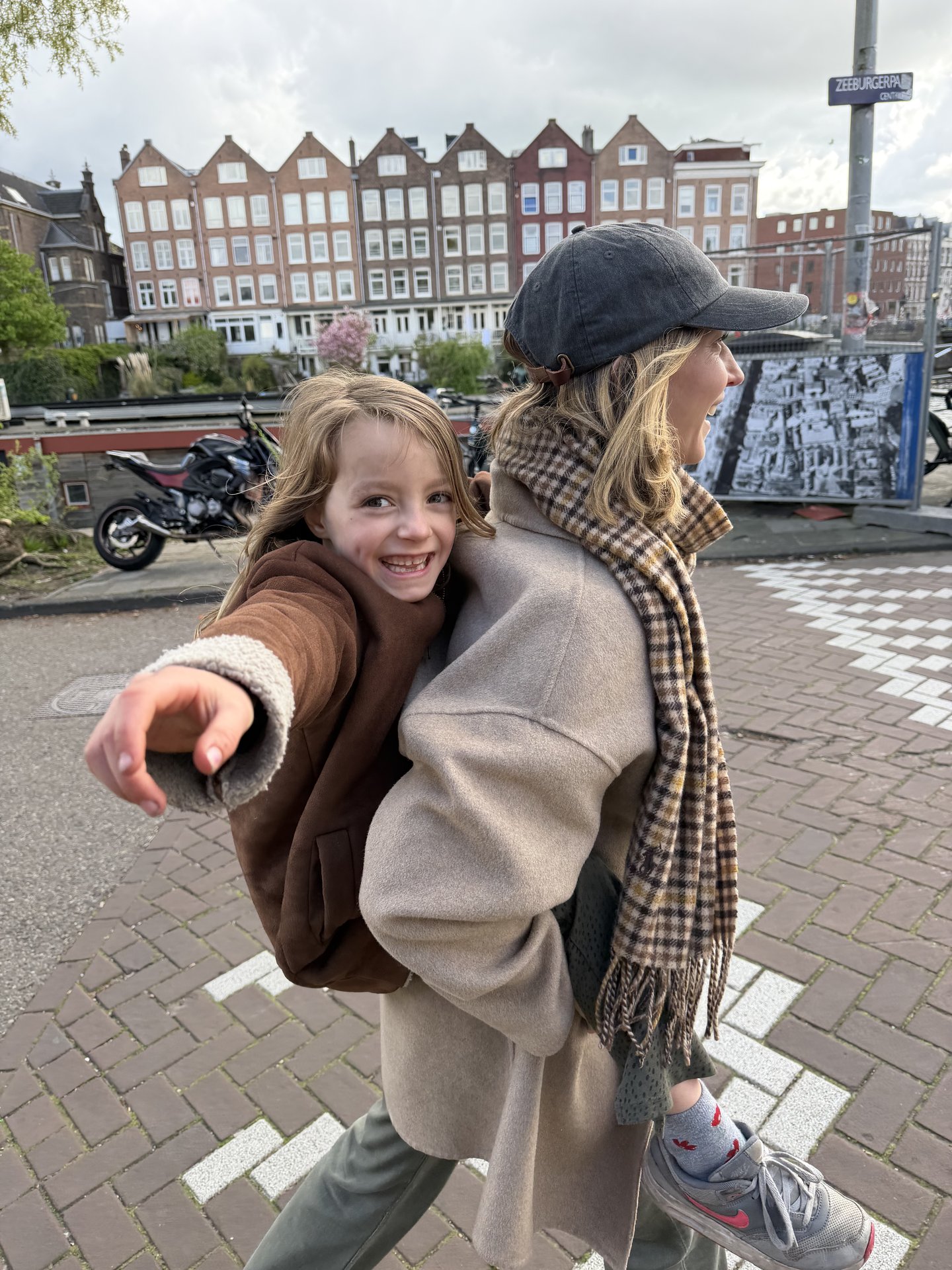 A joyful moment unfolds on Zeeburgerpad in Centrum, Amsterdam, where an adult carries a smiling child on their back